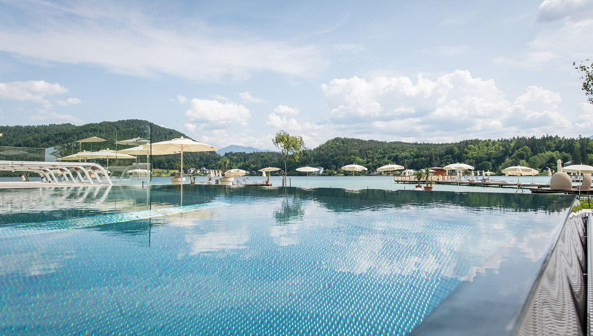 Blick über Pool zu See mit Badesteg